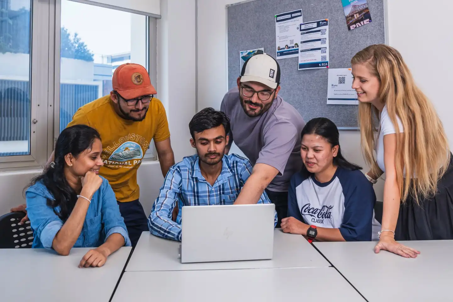 APIC students gathered around a laptop, discussing tuition fees and financial planning options.