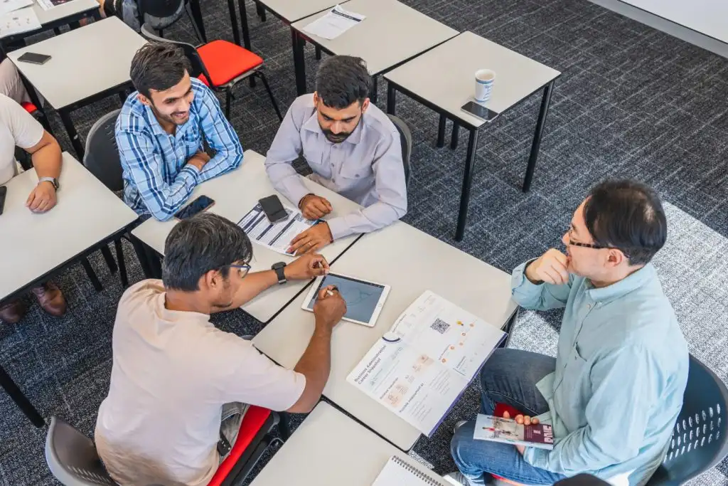 Group of APIC students seated around a table reviewing course materials and admission documents.