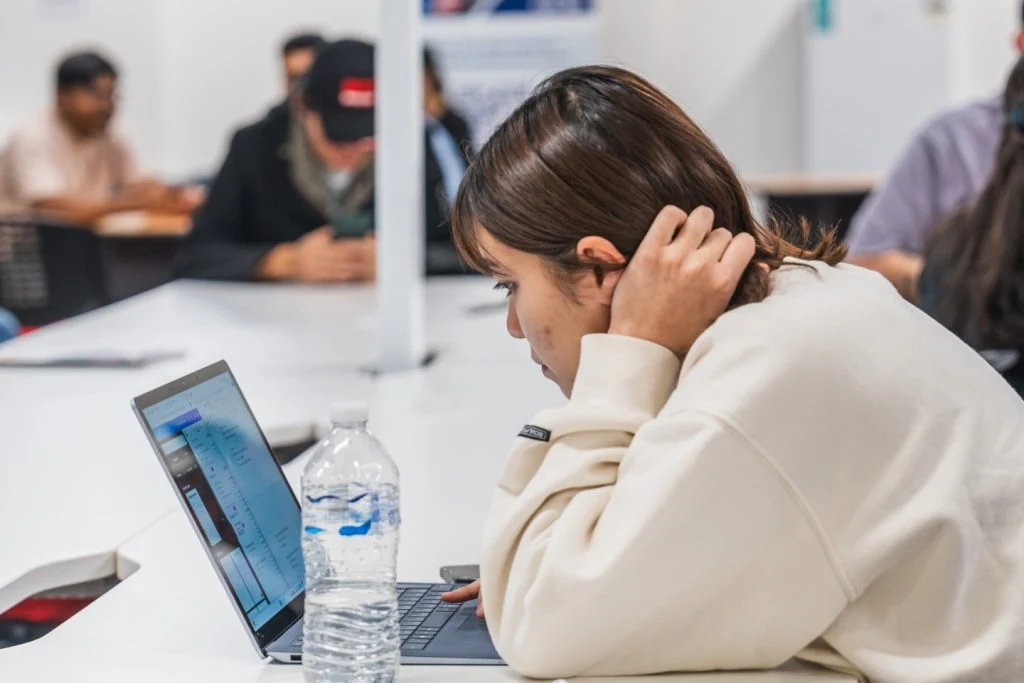 Female student studying at APIC with a laptop and water bottle during a postgraduate class.