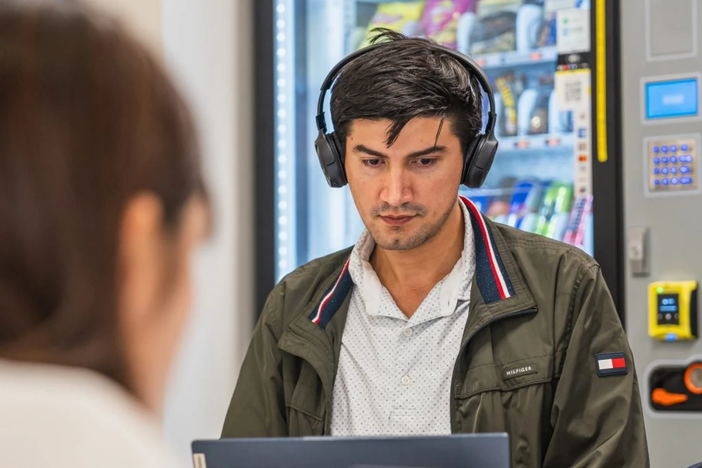 APIC undergraduate student wearing headphones and focused on a laptop in a collaborative study area.